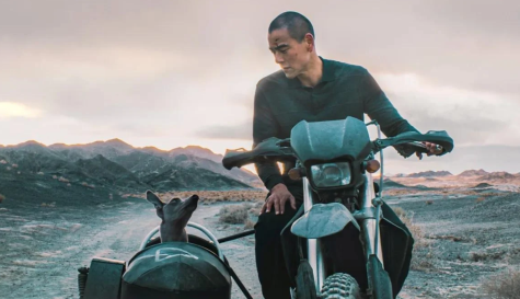Fotograma de 'Black Dog', de Guan Hu, protagonizada por Eddie Peng junto al perro negro que le acompaña en su travesía por el desierto de Gobi.