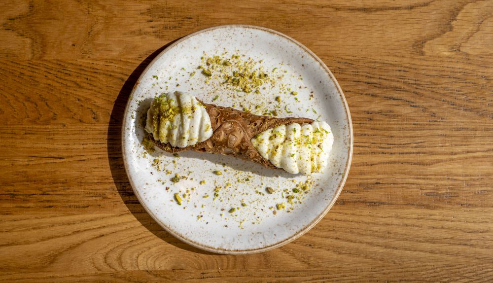 Un cannolo relleno de crema y con pistacho picado, en Al Pomodoro. / Al Pomodoro Un cannolo relleno de crema y con pistacho picado, en Al Pomodoro. / Al Pomodoro